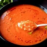 Roasted tomato quinoa soup in a bowl with a spoon.