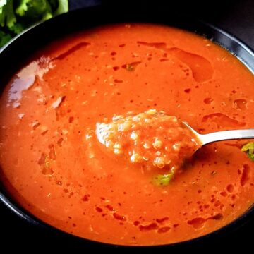 Roasted tomato quinoa soup in a bowl with a spoon.