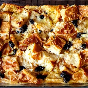 Bread pudding with black raisins in a baking dish.
