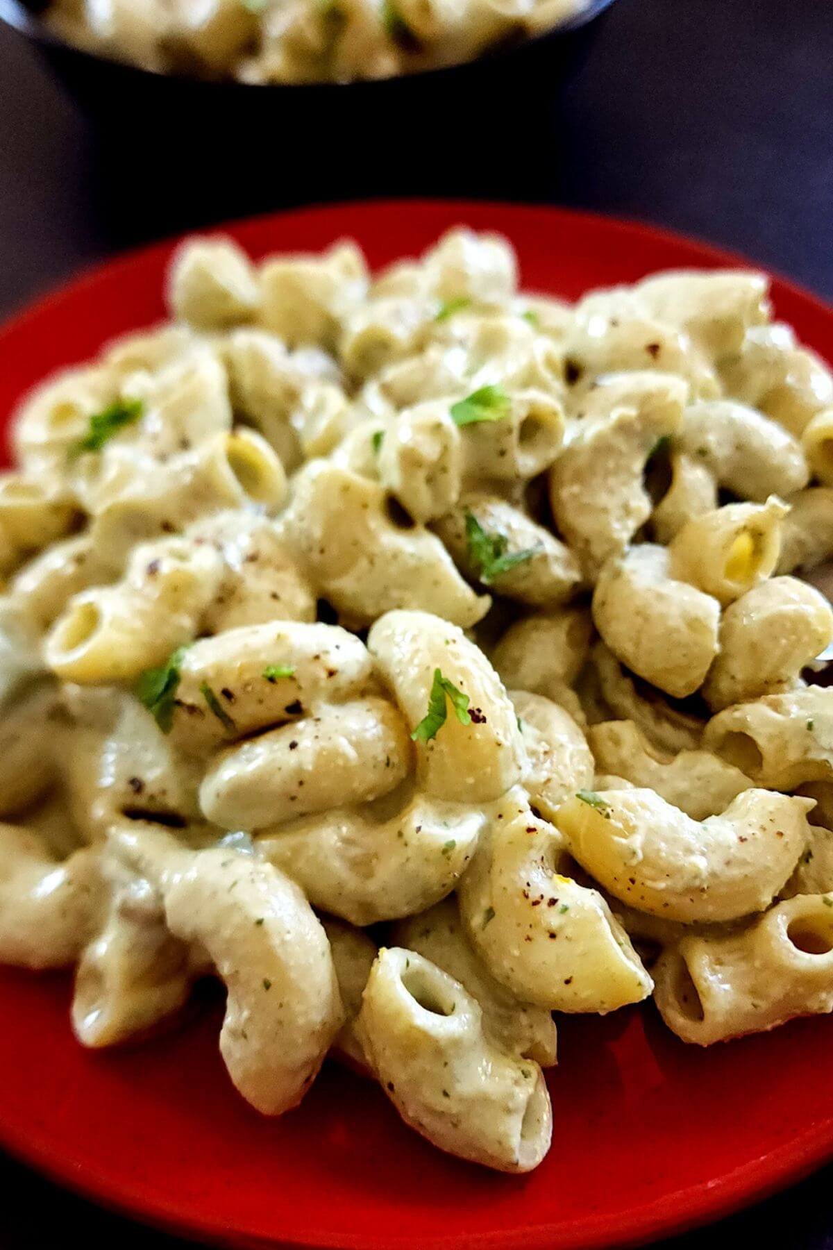 Ricotta and pesto pasta served on a red plate.
