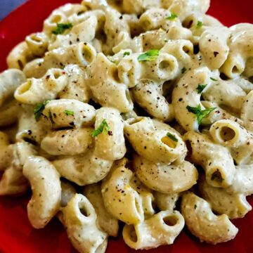 Pesto ricotta pasta served on a red plate.
