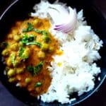 Green peas curry in a bowl with rice and sliced onion.