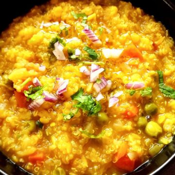 Quinoa khichdi garnished with chopped red onion and cilantro.