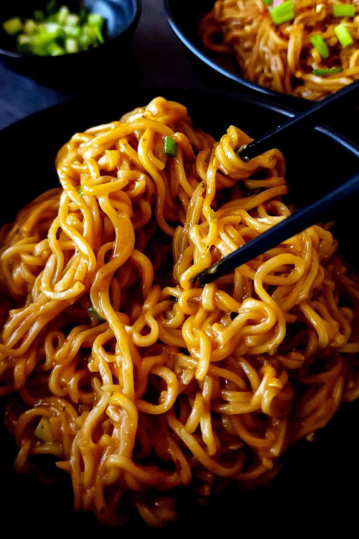 Spicy Korean cheese ramen in a bowl with a pair of chopsticks.