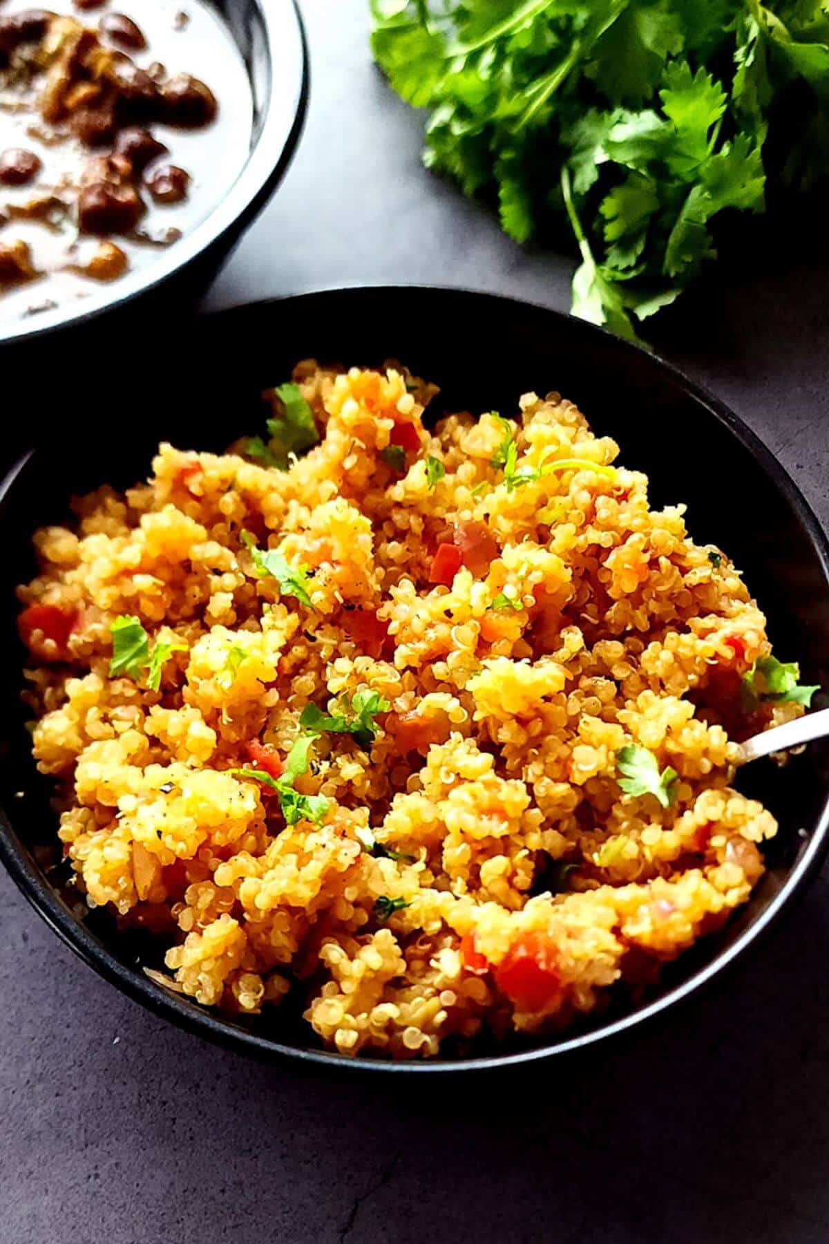 A bowl of vegan tomato quinoa with a spoon.