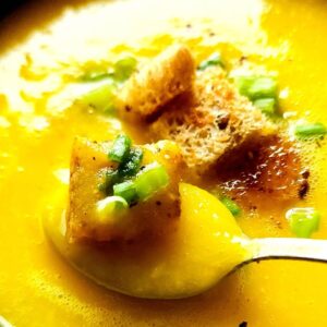 Yellow pepper soup topped with croutons and chopped green onions.