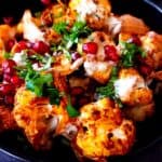 Roasted harissa cauliflower topped with tahini sauce, pomegranate arils, and chopped cilantro.