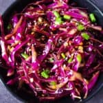 Spicy red cabbage in a black bowl.