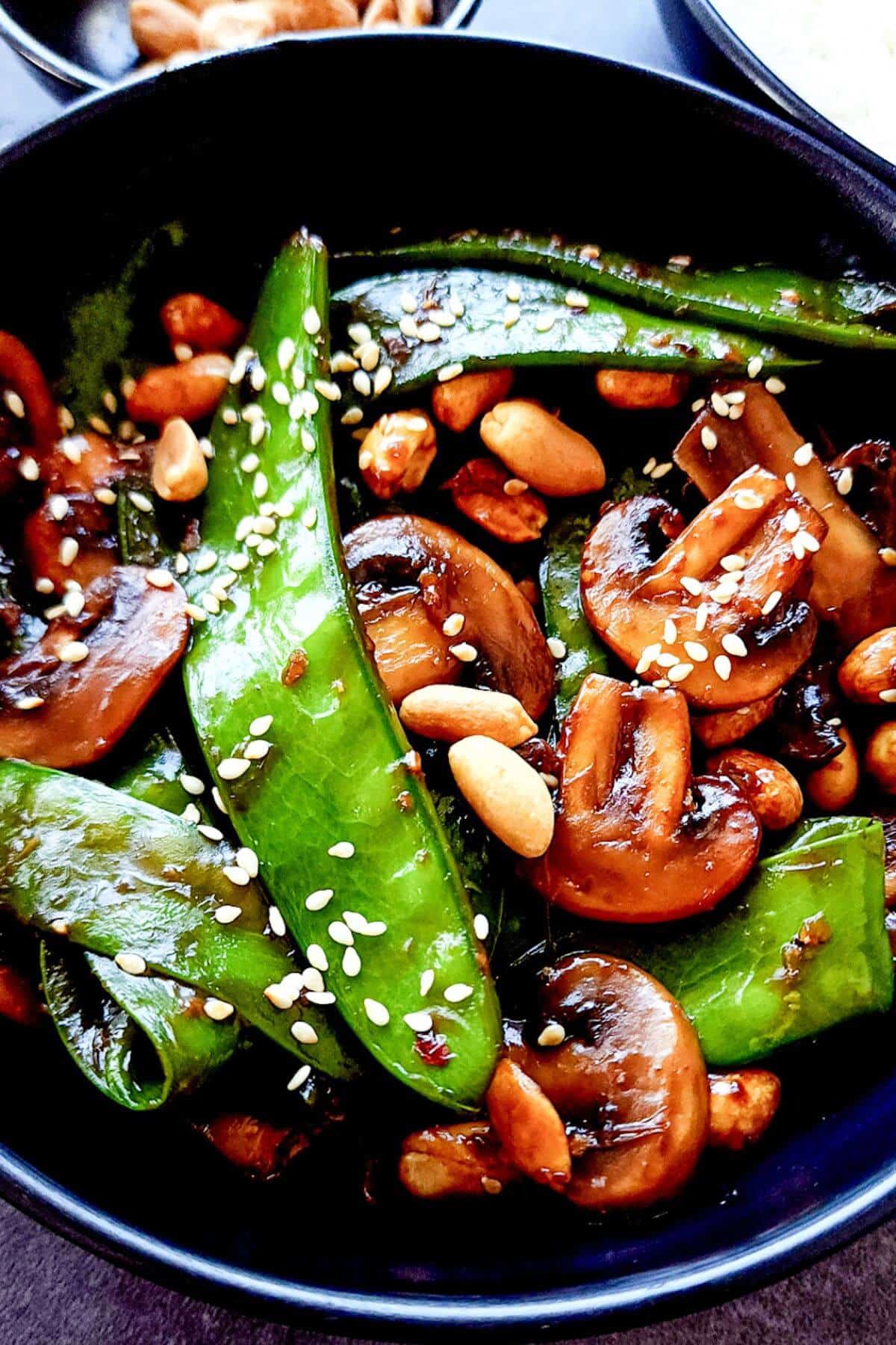 Asian stir fried mushrooms and snow peas in a bowl.