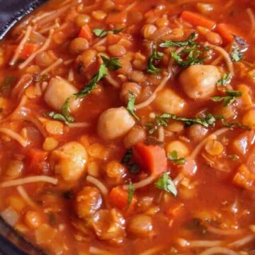 A bowl of vegetarian harira soup garnished with chopped fresh herbs.