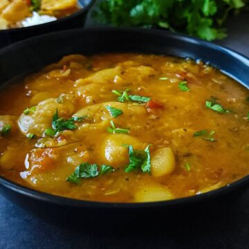 A bowl of butter bean curry garnished with chopped cilantro.
