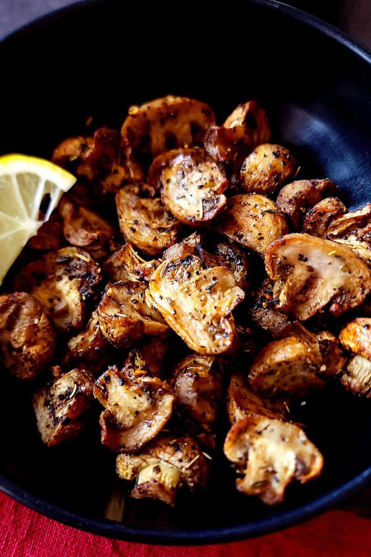 Air fryer mushrooms served in a bowl with a lemon wedge.
