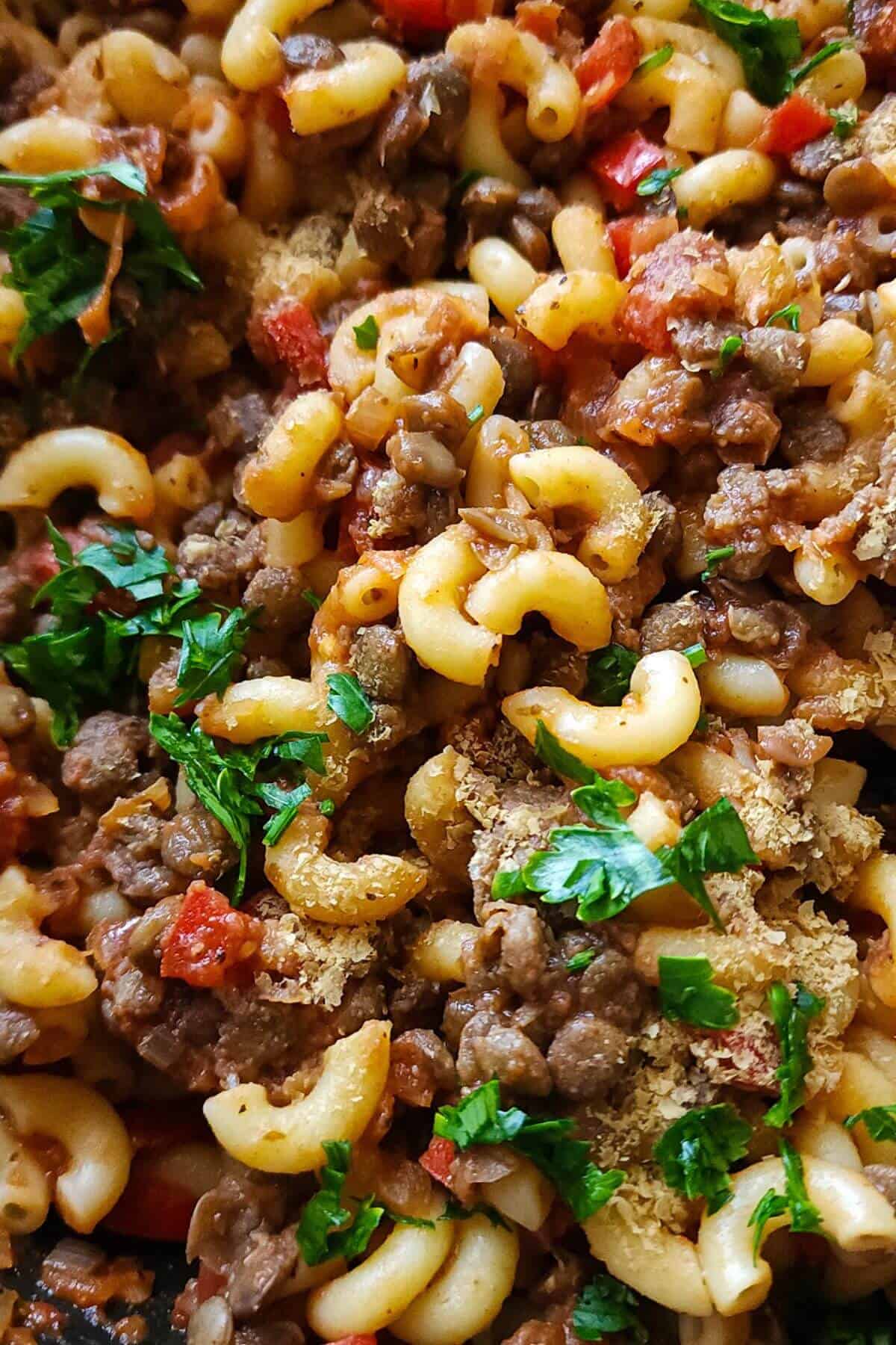 Lentils and pasta dish garnished with chopped parsley.