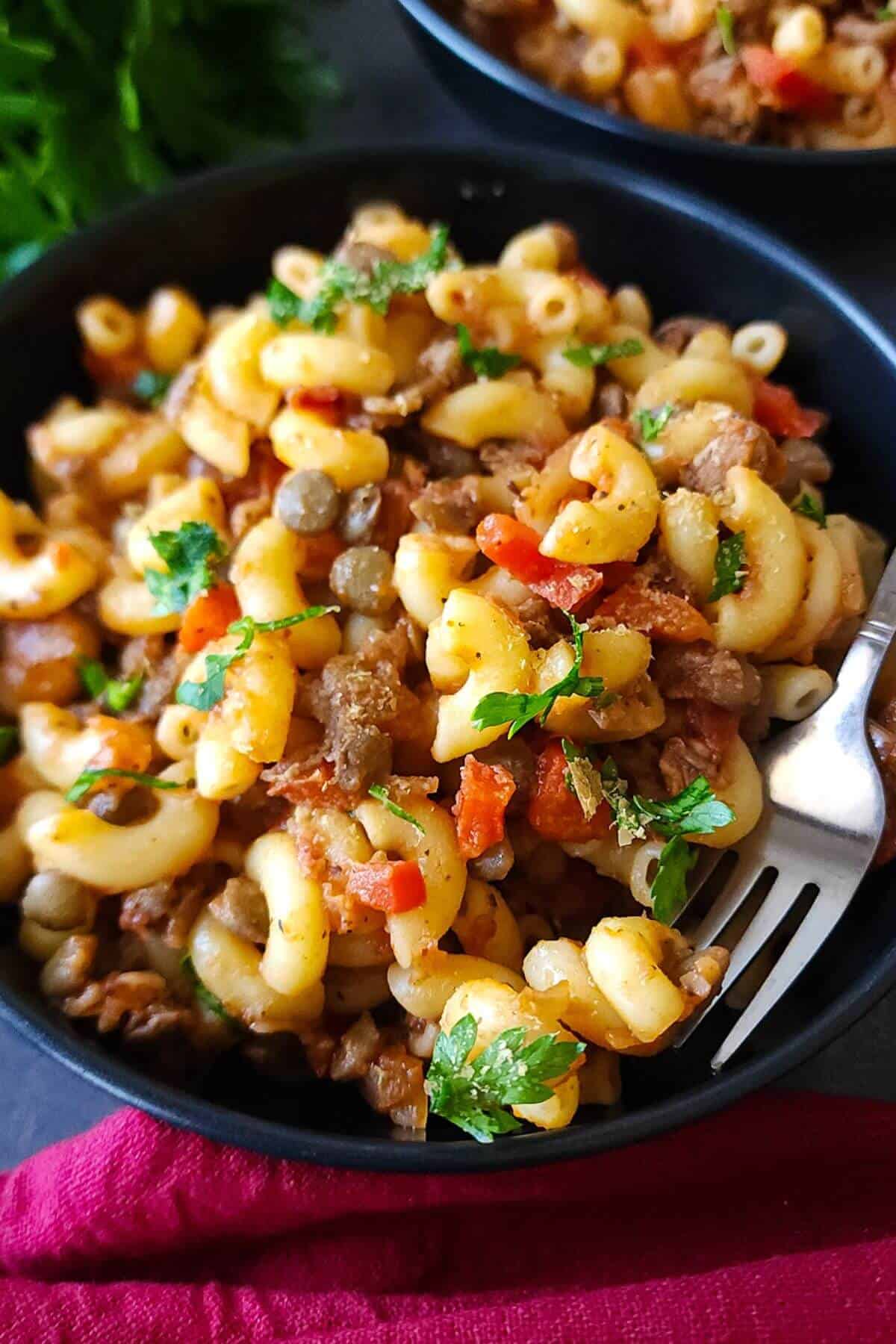 A bowl of lentils and pasta with a fork.